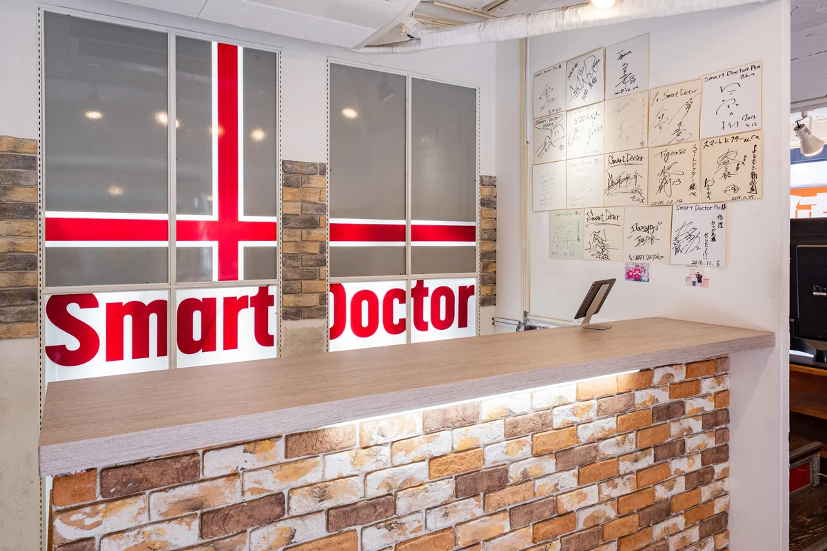 スマートドクタープロ大阪心斎橋本店の店内カウンター——お客様からの感謝の色紙が並ぶ。2009年創業・17年の実績と信頼の証。総務省登録修理業者（R000002/T000002）。
