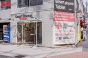 スマートドクタープロ心斎橋 外観側面——総務省登録修理業者・ISO9001:2015認証・電気通信事業法T000002・電波法R000002を掲示