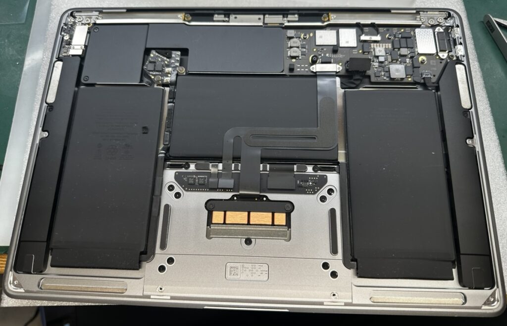MacBook Air M1を分解し、バッテリー・ロジックボード・トラックパッドなど内部の状態を確認している様子（実機写真）