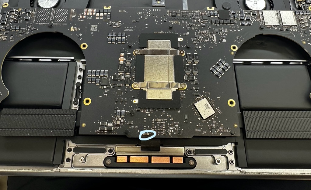 MacBook Pro M1の基板上で、水濡れにより焼損したコンデンサ・電源IC（青い丸で示した箇所）を特定した実機写真