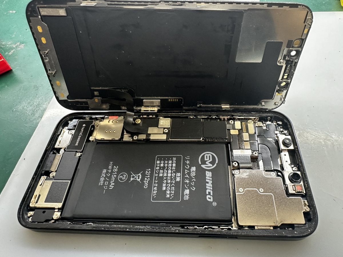 水没したiPhone 12の内部。基板と他社で交換されたバッテリーが確認できる|電源IC・コンデンサー交換の基板修理
