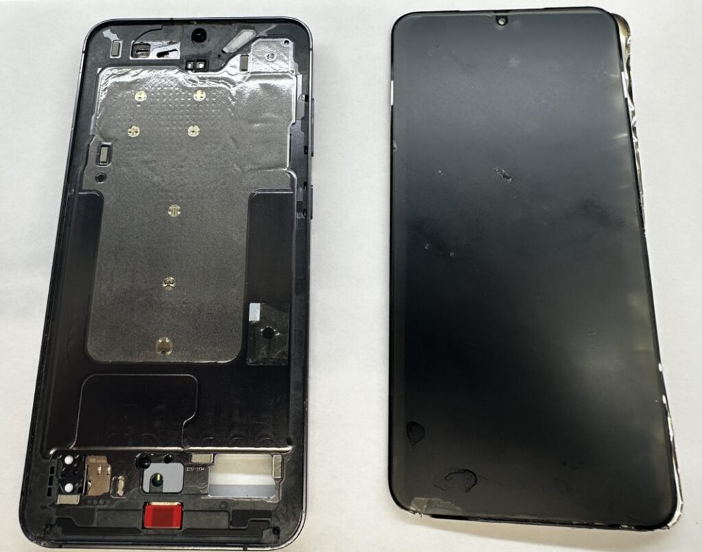Galaxy S23 Ultraを分解し、フレームと取り外した割れた有機ELパネルを並べた様子。接着を剥がして新しい画面へ交換する