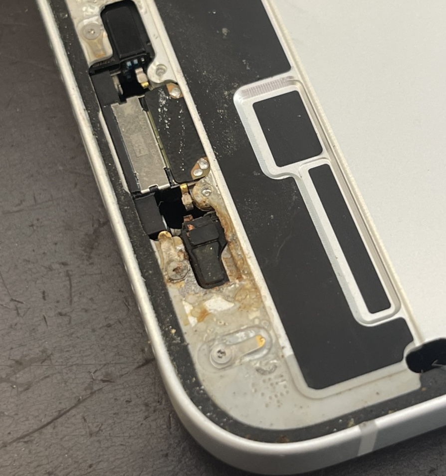 iPhone 16eの筐体。充電口・スピーカー周辺に海水没による白い塩の析出と錆・腐食