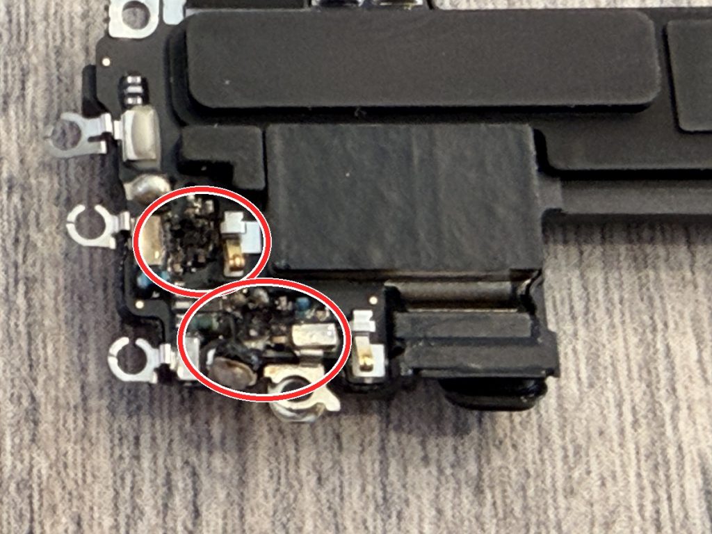 iPhone 16の電波系ICの熱損傷を別アングルで撮影し、損傷箇所を赤い丸で示した写真
