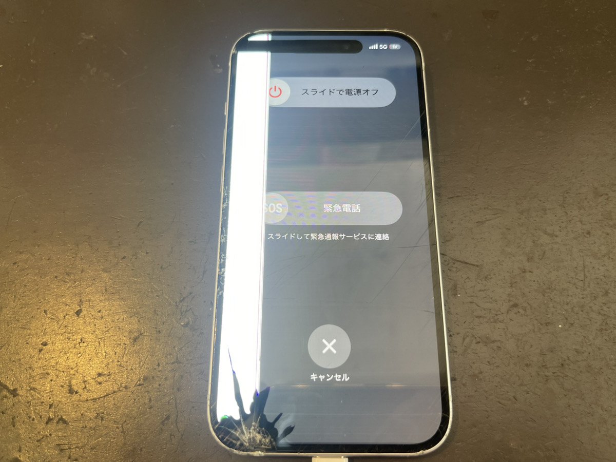 落下後のiPhone 15。画面左側に白い縦の帯が出ていて、左下の角のガラスが割れている