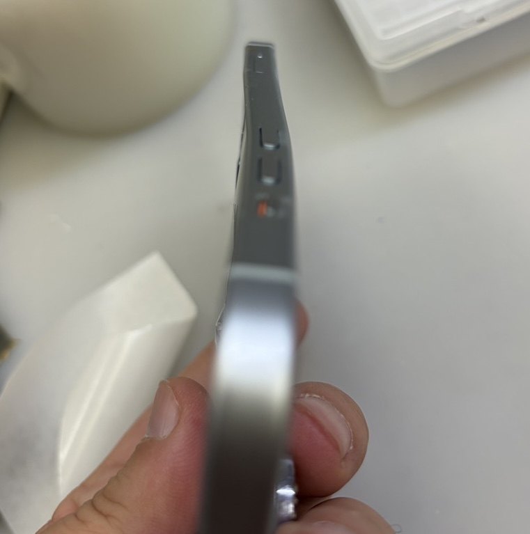 iPhone 15を側面から手に持って見たところ。フレームが大きく波打って曲がっている