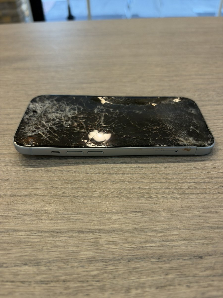 割れた画面のiPhone 15を低い角度から見たところ。側面のフレームが曲がっているのが分かる