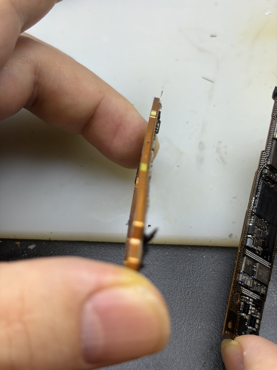iPhone 15の基板を横から見た写真。基板が曲がって反りが出ている