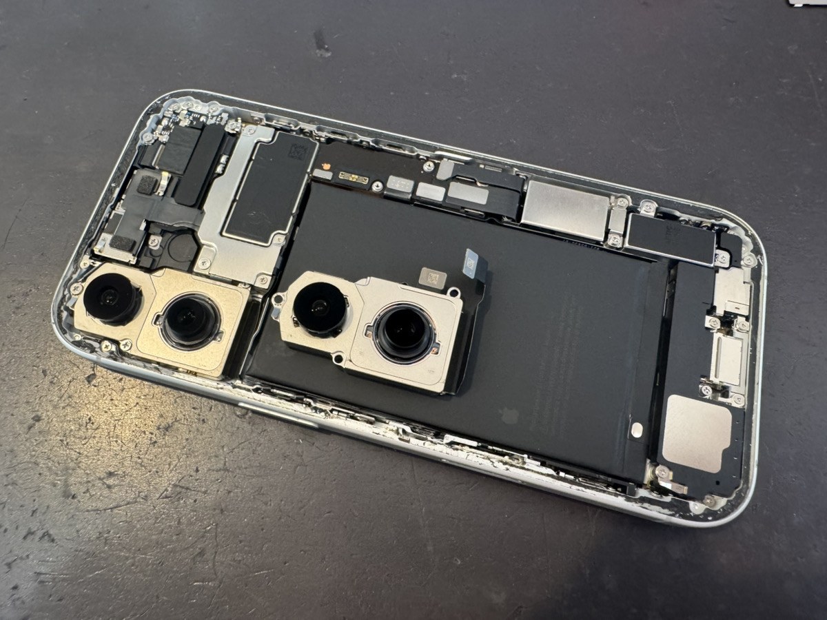 iPhone 17を開けた内部。左に取り外す前のカメラユニット、右に青いシールのついた新しいカメラユニットが並んでいる